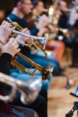 A musician playing a trumpet in a trumpet section of an orchestra during rehearsal © Janisphoto