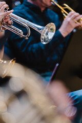 A musician playing a trumpet in a trumpet section of an orchestra during rehearsal © Janisphoto