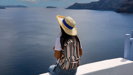 Fototapeta na wymiar Back view young tourist girl happy lifestyle and enjoy in Summer time with blue sky at Oia,Santorini in Greece