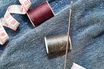 needles measuring tape and thread on the background of torn jeans the concept of reasonable consumption of needlework for small businesses