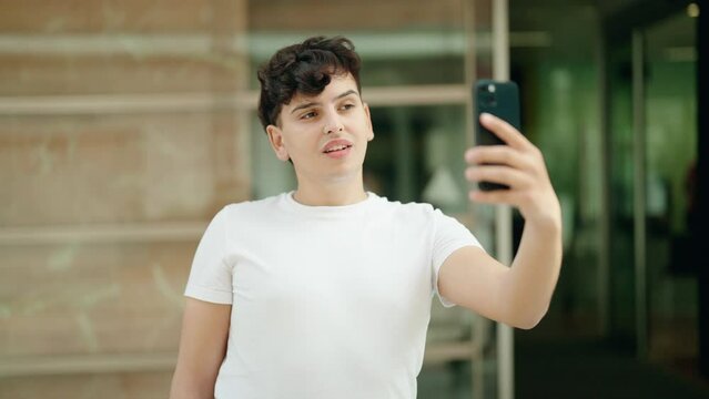 Non binary man smiling confident making selfie by the smartphone at street
