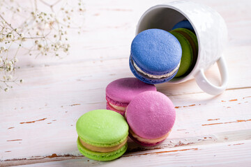 Colorful macaroons crumble from a white cup