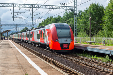 Suburban modern electric train stands at a rural station. Travel and tourism.