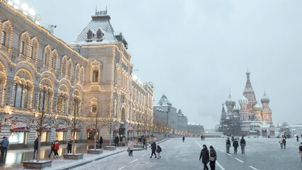 Beautiful city square on a snowy day before the New Year holidays. Action. People walking in front...