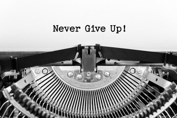 Never Give Up phrase close up being typing and centered on a sheet of paper on old vintage typewriter mechanical - obrazy, fototapety, plakaty