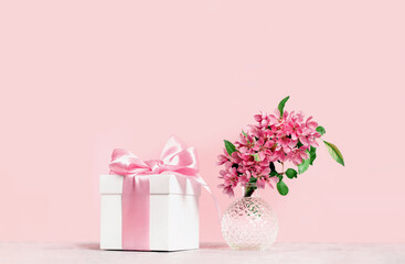 Pink pastel holiday. gift box and spring or summer flowers branch in a crystal ball vase. Monochrome., birthday or wedding. Valentines or Mothers day