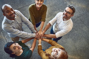 Were in this to win this. High angle portrait of a group of colleagues joining their hands in...