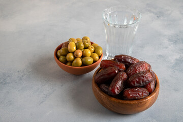 Date fruit, olives and a glass of water.Traditional ramadan table