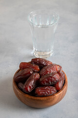 Glass of water with a bowl of date fruit on bright background

