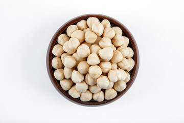 Bowl full of peeled hazelnuts on white background,top view