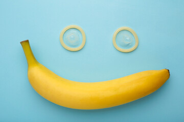 Condom and banana on blue background with copy space