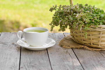 Fresh natural green melissa herbal tea in white cup. Organic aromatherapy relaxation medical healthy beverage. Rustic wooden table background. Rustic style natural light.