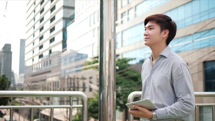 Portrait of happy Asian businessman walking on the street in the modern city with building background at outdoor