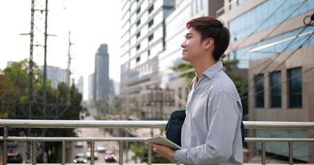 Portrait of happy Asian businessman walking on the street in the modern city with building background at outdoor