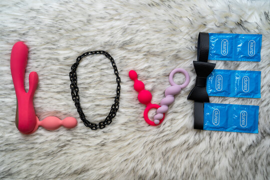 the word love made of sex toys and Durex condoms on gray fur background, adult content