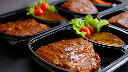 Grilled and smoked pork ribs in takeaway box.