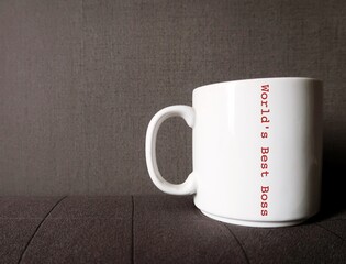 White mug on dark grey copy space background with text WORLD BEST BOSS, concept of beloved boss, supervisor who doing his best to support to staff and put their best foot forward