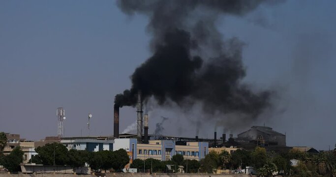 Smoke billows from the chimneys stacks of a sugar refinery which sits on the bank of the River Nile south of Luxor in Egypt.
