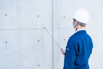 打診棒を持つ作業着を着た日本人男性