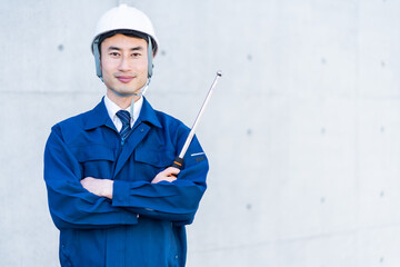 打診棒を持つ作業着を着た日本人男性