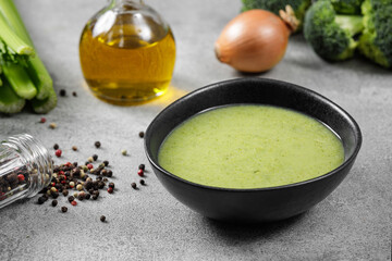 Cream soup with broccoli in a black plate on a gray background