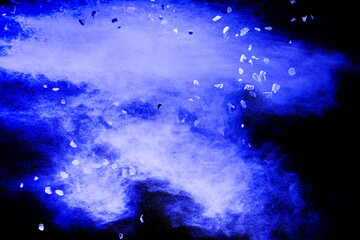 Split debris of stone exploding with blue  powder against black background.