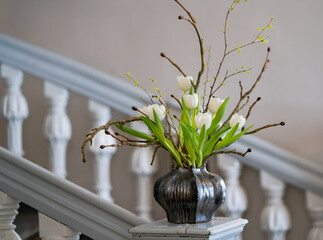 Simple spring flower arrangement of white tulips and blossoming branches.