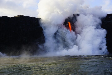Hot lava stream flowing down from high cliff  into the ocean surrouded by white steam