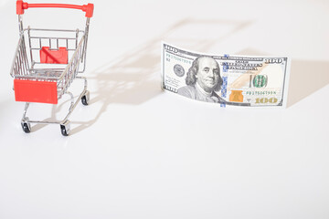 shopping cart with 100 dollar american banknote. Consumption, shopping concept, trolley. Empty...