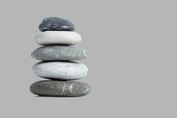 Pyramid of beautiful sea stones. Peace and tranquility of soul and body. Isolated on a gray background. Space for text.