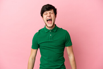 Young Russian man isolated on pink background shouting to the front with mouth wide open