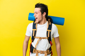 Young mountaineer Russian man with a big backpack isolated on yellow background looking side