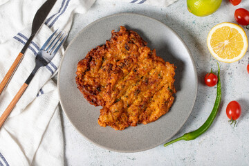 Mucver on the gray background. Frying dinner made of pumpkin. Top view