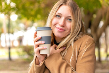 Young pretty blonde woman holding a take away coffee at outdoors