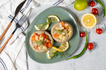 Artichoke with vegetables on gray floor. Artichoke dinner made with olive oil, potatoes, carrots and onions. Healthy food. Top view