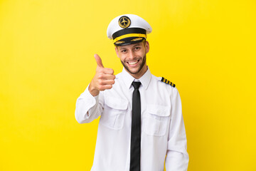 Airplane caucasian pilot isolated on yellow background with thumbs up because something good has happened