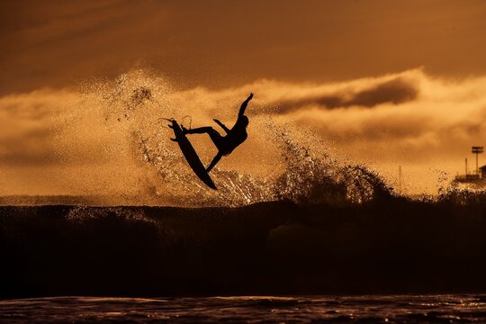 Surfer taking flight on a wave into the evening light