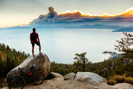 A mountain biker stops on the Flume Trail to watch smoke from a wildfire.