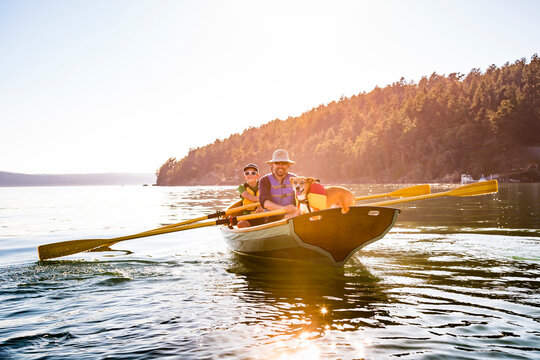 A Man With His Son And Their Dog In A Rowing Boat In Deer Harbor, Orcas Island, Washington, Usa