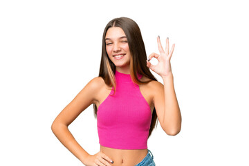 Teenager caucasian girl over isolated background showing ok sign with fingers