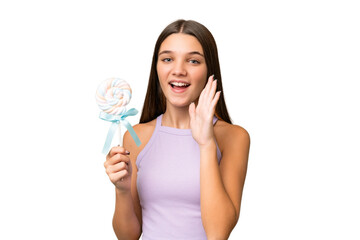 Teenager caucasian girl holding a lollipop over isolated background shouting with mouth wide open