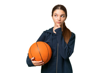 Teenager caucasian girl playing basketball over isolated background and looking up