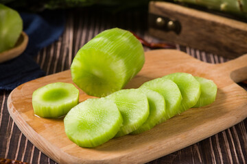 Fresh peeled asparagus lettuce on wooden table.