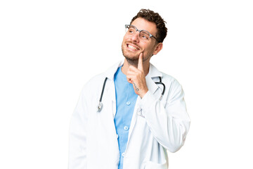 Fototapeta premium Brazilian doctor man over isolated chroma key background thinking an idea while looking up