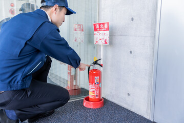 消火器を点検する作業服を着た日本人男性