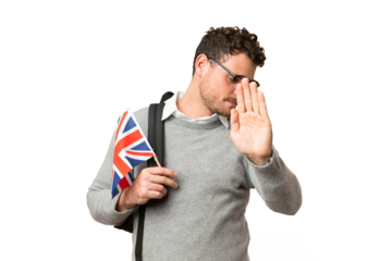 Brazilian man holding an United Kingdom flag over isolated chroma key background making stop gesture and disappointed