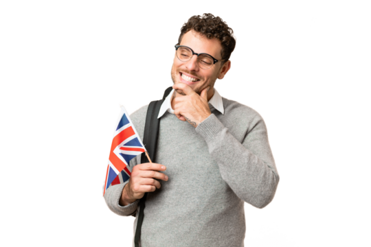 Brazilian man holding an United Kingdom flag over isolated chroma key background looking to the side and smiling