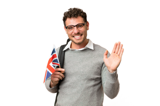 Brazilian man holding an United Kingdom flag over isolated chroma key background saluting with hand with happy expression