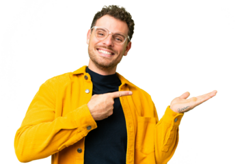 Brazilian man over isolated chroma key background holding copyspace imaginary on the palm to insert an ad