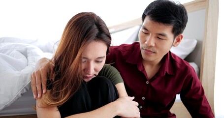 Loving Asian man trying reconcile with his wife after quarrel. Guy embracing his crying suppose...